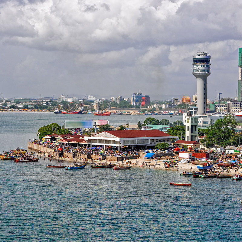Fisherman boats in front of Kivukoni fish market with Port control tower and Skyscrapers Behind, Dar Es Salaam, Tanzania